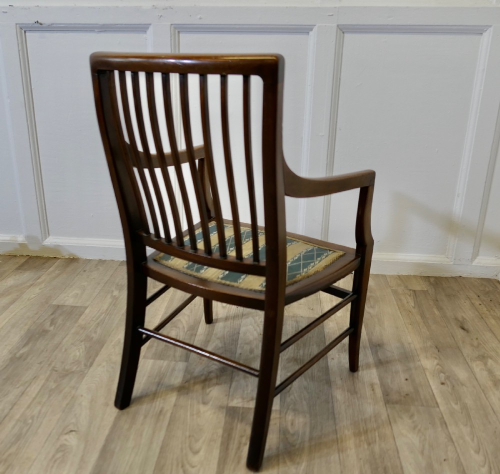 A dark mahogany Regency style childs open armchair with vertical back splats, sweeping armrests, and a striped fabric seat. View IV
