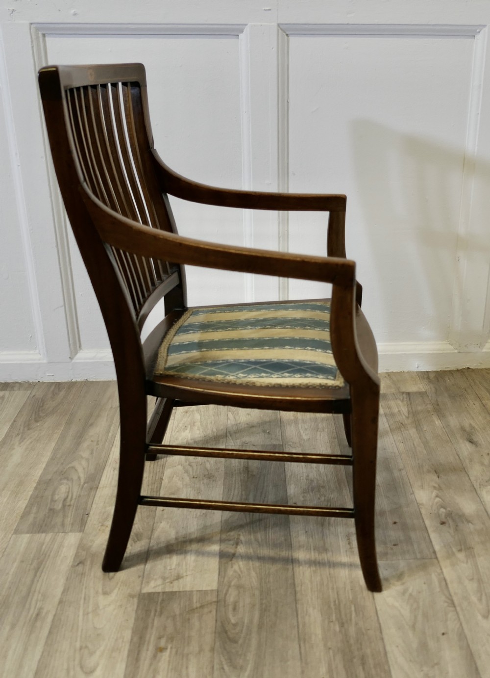 A dark mahogany Regency style childs open armchair with vertical back splats, sweeping armrests, and a striped fabric seat. View V