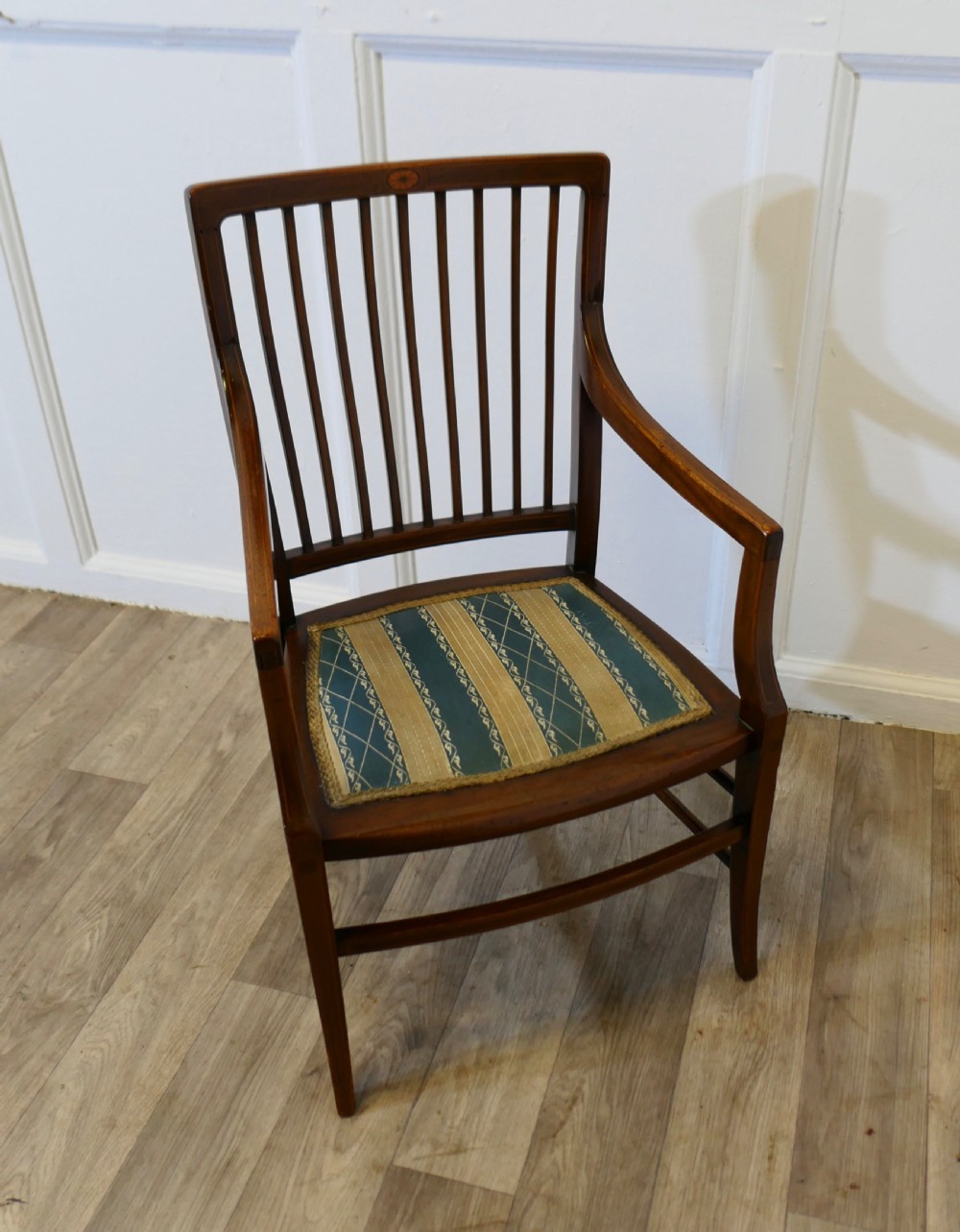 A dark mahogany Regency style childs open armchair with vertical back splats, sweeping armrests, and a striped fabric seat. View VI