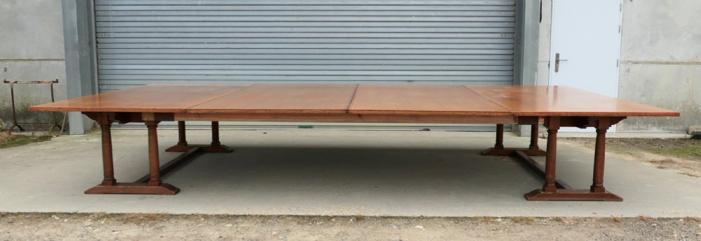 An exceptionally long Arts and Crafts solid oak banqueting table supported by columned trestle bases and structural stretchers.