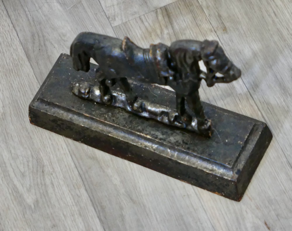 A dark cast iron doorstop featuring a saddled horse standing on a rectangular plinth base. View III