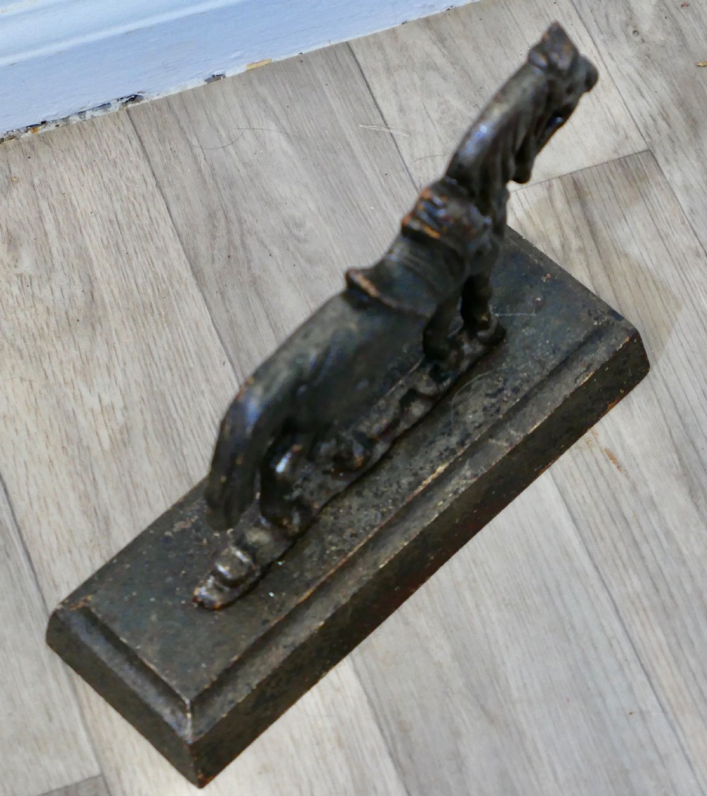 A dark cast iron doorstop featuring a saddled horse standing on a rectangular plinth base. View IV