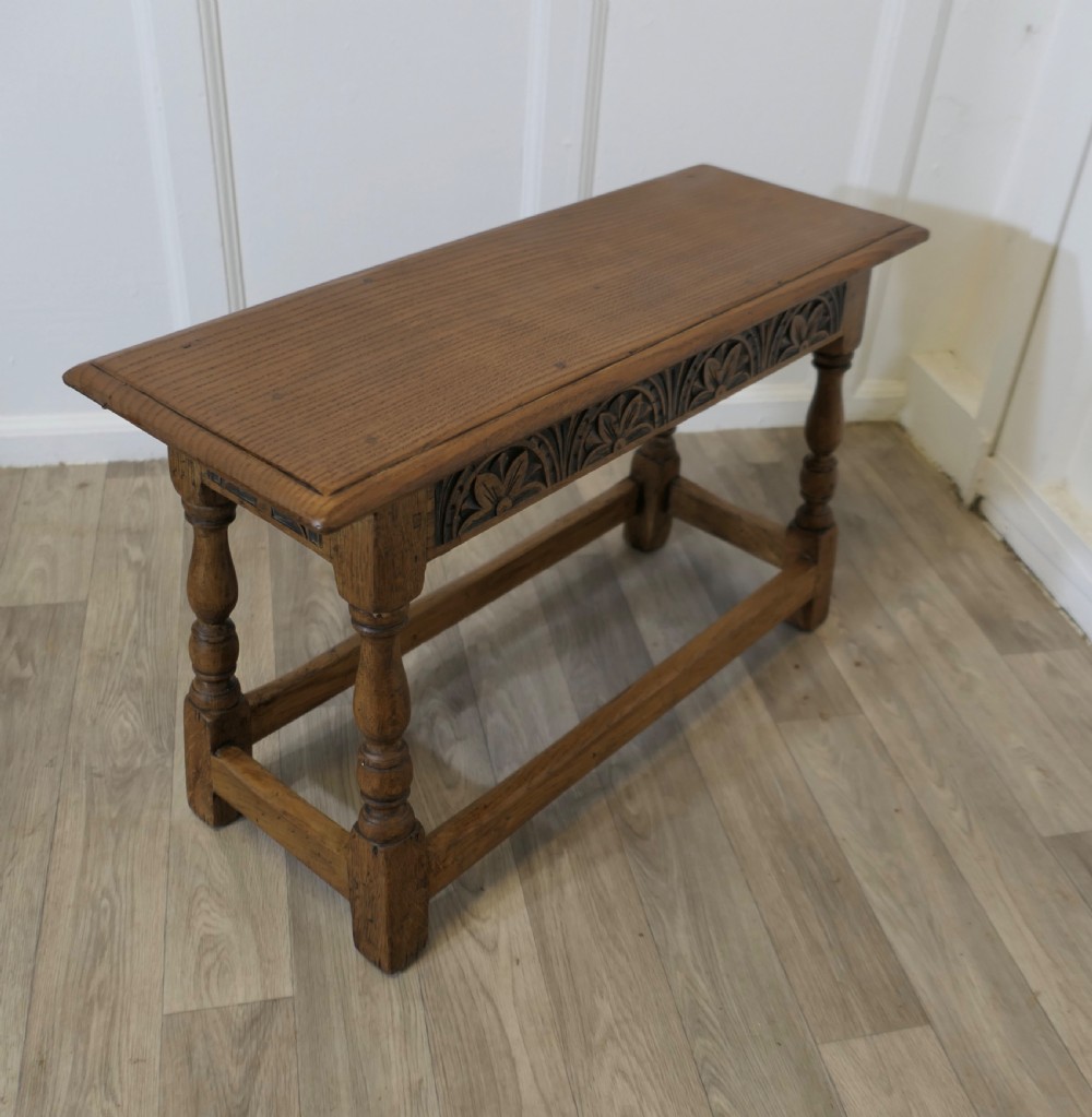 A golden oak joint stool featuring a carved frieze apron, turned legs, and low box stretchers. View III