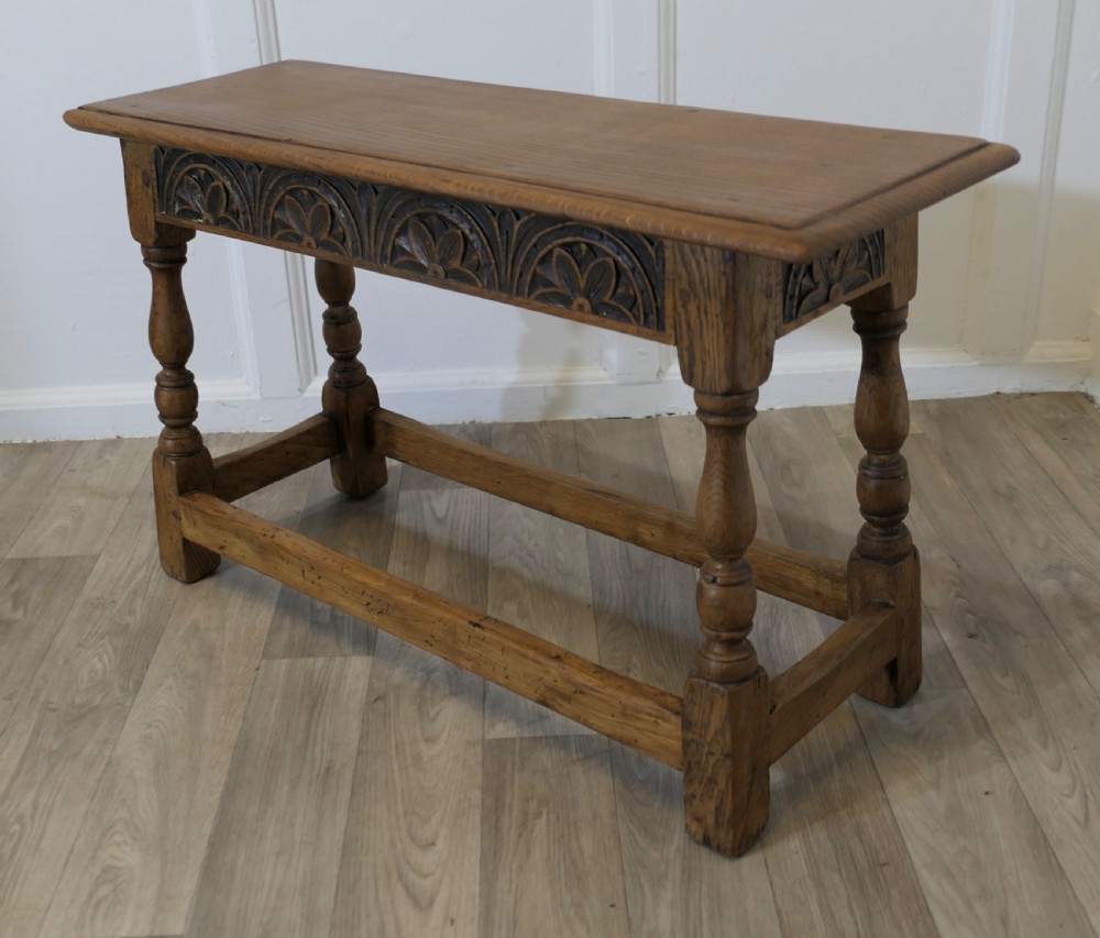 A golden oak joint stool featuring a carved frieze apron, turned legs, and low box stretchers. View VI