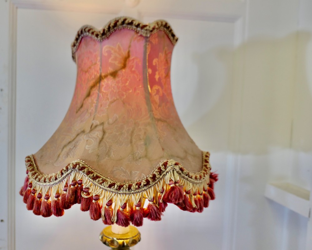 An antique French floor lamp with a gilded metal base, a velvet-wrapped central column, and a pink fabric lampshade featuring detailed fringe tassels. View VIII