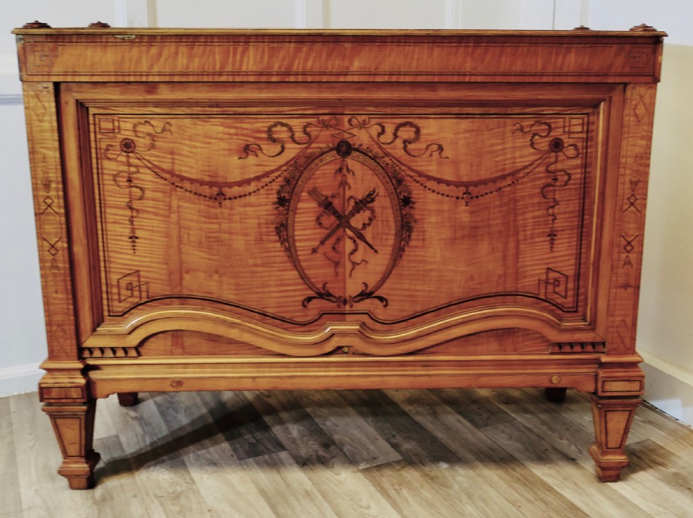 A French satin walnut jardiniere featuring intricate marquetry inlay of swags, bow motifs, and a central torch medallion, raised on square tapered legs.