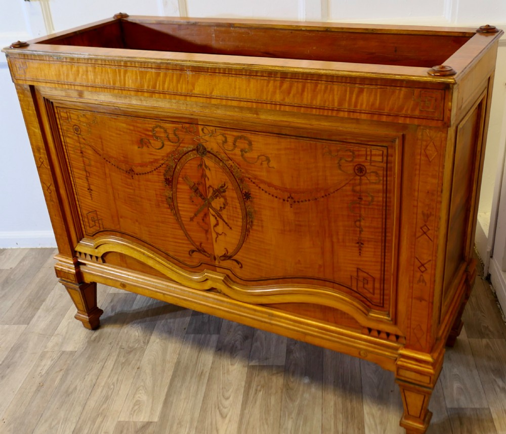 A French satin walnut jardiniere featuring intricate marquetry inlay of swags, bow motifs, and a central torch medallion, raised on square tapered legs. View V