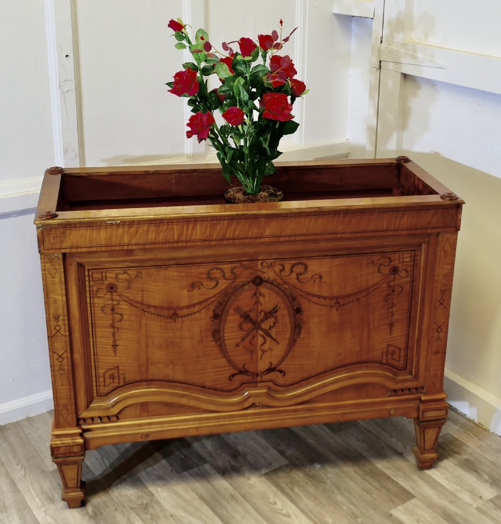 A French satin walnut jardiniere featuring intricate marquetry inlay of swags, bow motifs, and a central torch medallion, raised on square tapered legs. View VI