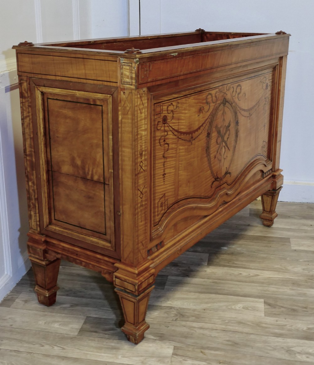 A French satin walnut jardiniere featuring intricate marquetry inlay of swags, bow motifs, and a central torch medallion, raised on square tapered legs. View VIII