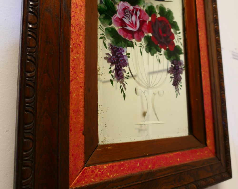 A rectangular Victorian wall mirror featuring a carved wooden frame, a red border, and a central reverse-painted glass panel displaying red roses and a bird in a vase. View IV