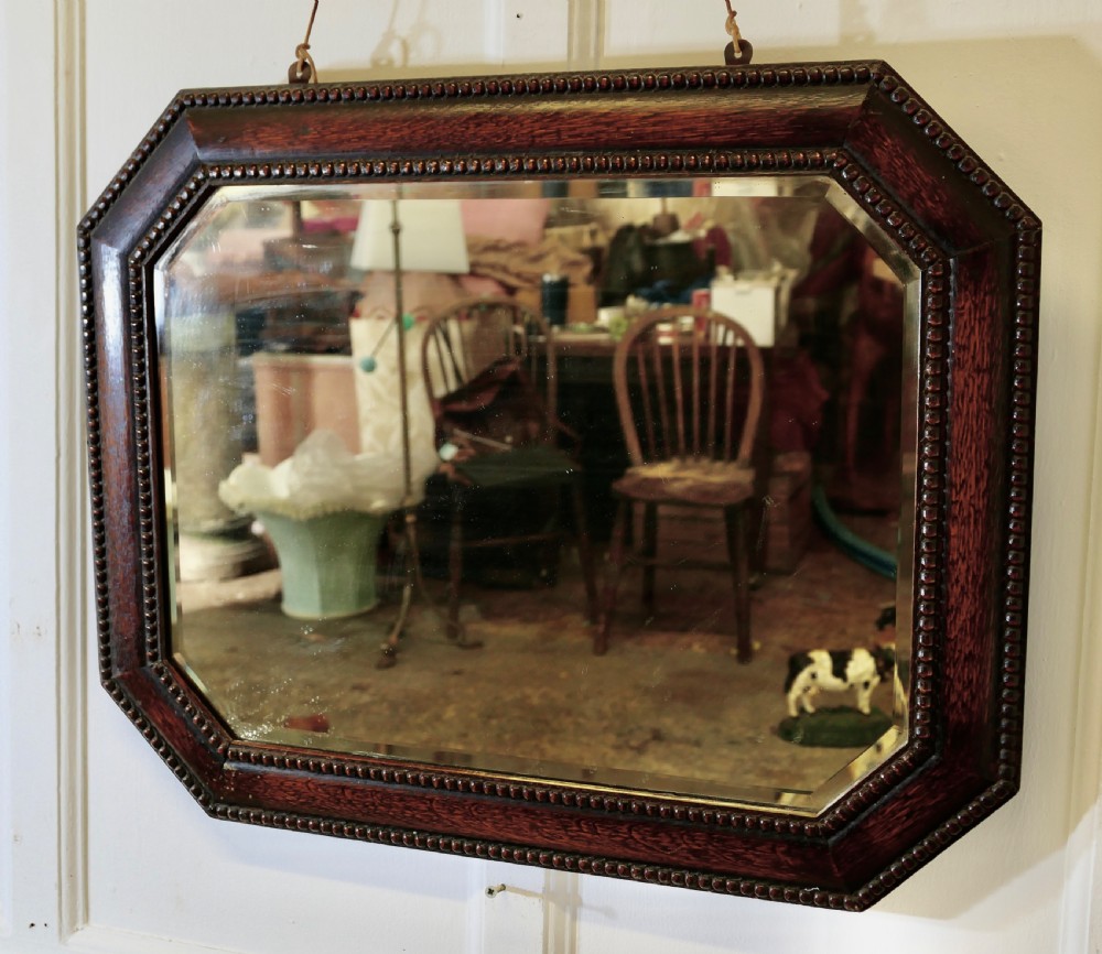 An octagonal dark-stained oak wall mirror featuring beaded moulding along the frame and a bevelled mirror plate. View III