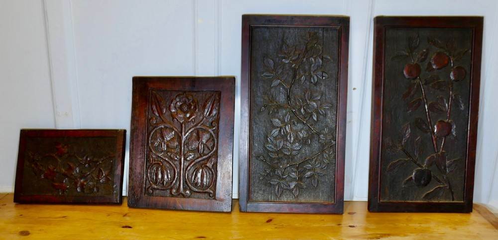 A set of four dark brown hand-carved oak panels featuring detailed botanical and floral relief motifs framed in rectangular timber borders.