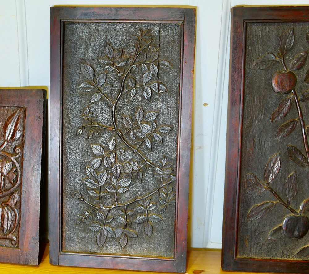 A set of four dark brown hand-carved oak panels featuring detailed botanical and floral relief motifs framed in rectangular timber borders. View III