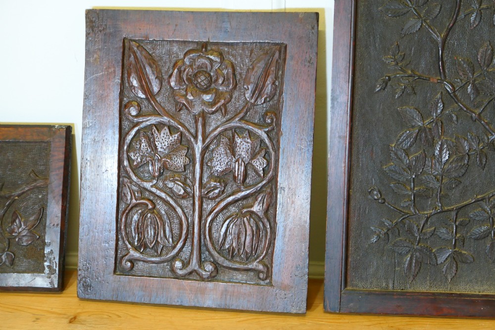 A set of four dark brown hand-carved oak panels featuring detailed botanical and floral relief motifs framed in rectangular timber borders. View IV
