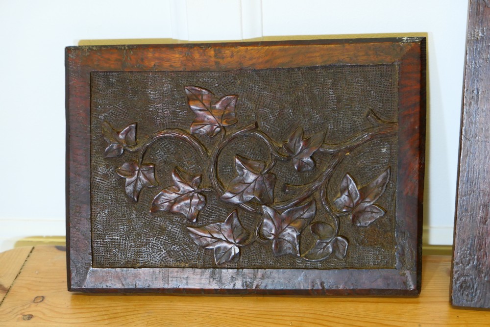 A set of four dark brown hand-carved oak panels featuring detailed botanical and floral relief motifs framed in rectangular timber borders. View V