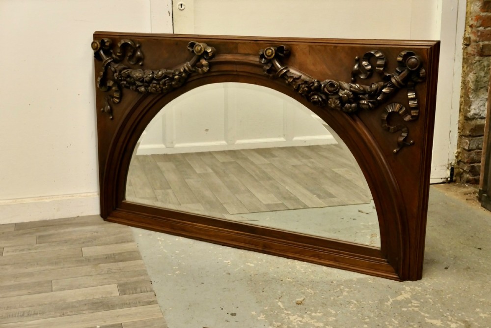 Large rectangular walnut overmantel mirror featuring an arched glass plate decorated with hand-carved floral swags and ribbons. View II