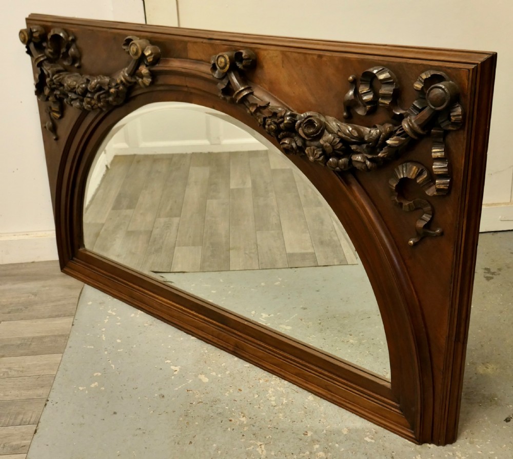 Large rectangular walnut overmantel mirror featuring an arched glass plate decorated with hand-carved floral swags and ribbons. View III