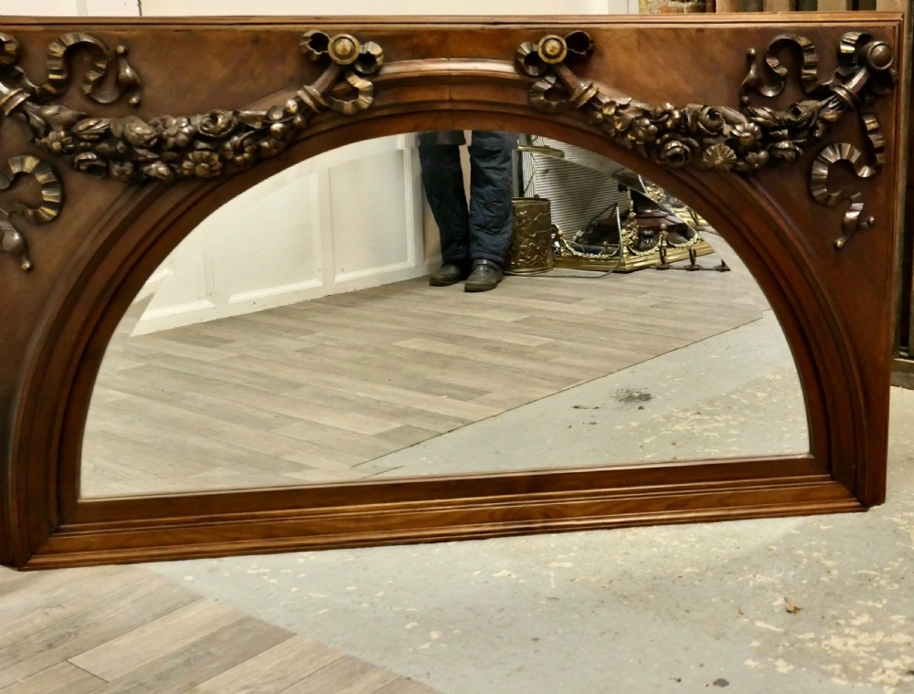 Large rectangular walnut overmantel mirror featuring an arched glass plate decorated with hand-carved floral swags and ribbons. View IV