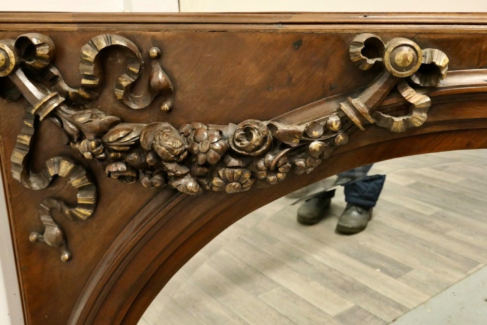 Large rectangular walnut overmantel mirror featuring an arched glass plate decorated with hand-carved floral swags and ribbons. View VI