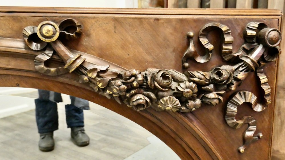Large rectangular walnut overmantel mirror featuring an arched glass plate decorated with hand-carved floral swags and ribbons. View VIII