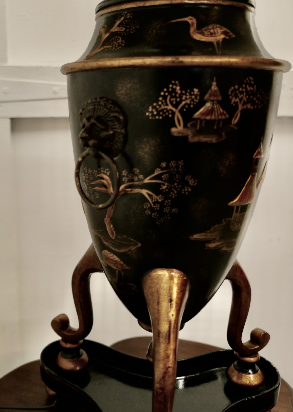 A black and gold lacquered Chinoiserie toleware table lamp decorated with oriental motifs, featuring lion head ring handles, tripod cabriole legs, and a conical metal shade. View XI