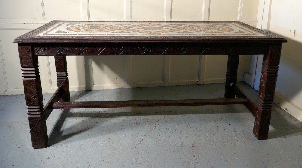 A rectangular dark wood dining table featuring a detailed geometric stone mosaic top, hand-carved geometric patterns on the apron, and carved legs connected by stretchers. View II