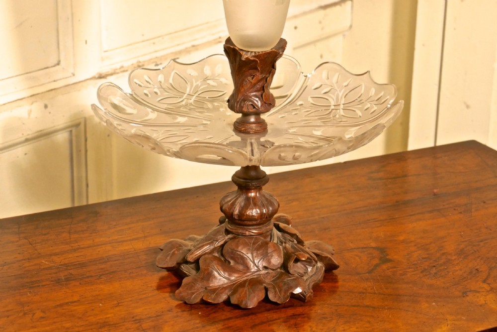 A Victorian Black Forest carved wooden epergne with a leaf base supporting a shallow etched crystal dish and a tall frosted trumpet vase. View II