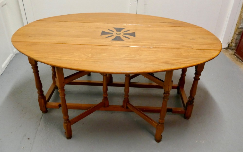 An oval wooden gateleg dining table featuring a central geometric star inlay, turned legs, and foldable drop leaves. View III