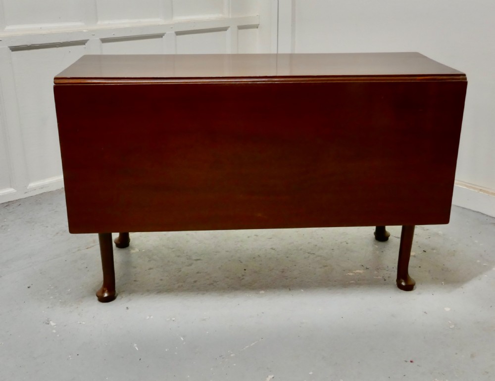 Folded Georgian mahogany drop-leaf dining table with straight turned legs terminating in pad feet.