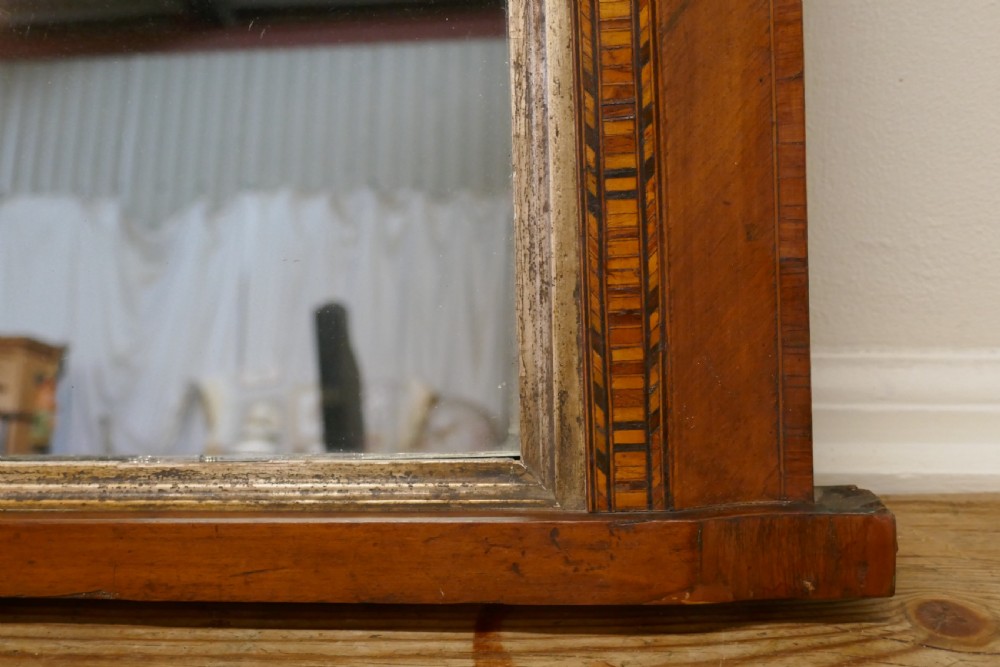 A Victorian walnut overmantel mirror featuring rounded upper corners, an intricate mosaic Tunbridge ware inlay border, and a gilt inner slip frame. View V