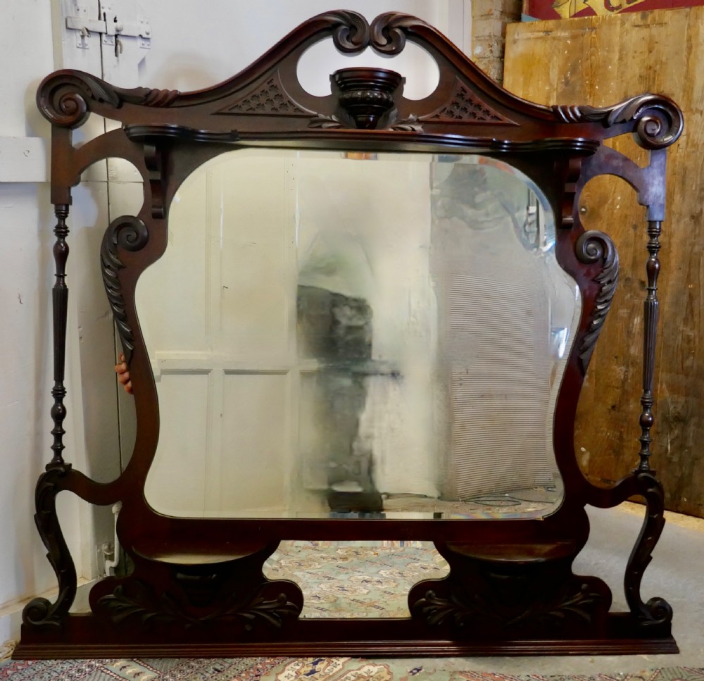 A large carved mahogany overmantel mirror in the Chinese Chippendale style, featuring pierced fretwork, turned side supports, side display shelves, and a shaped glass plate. View II