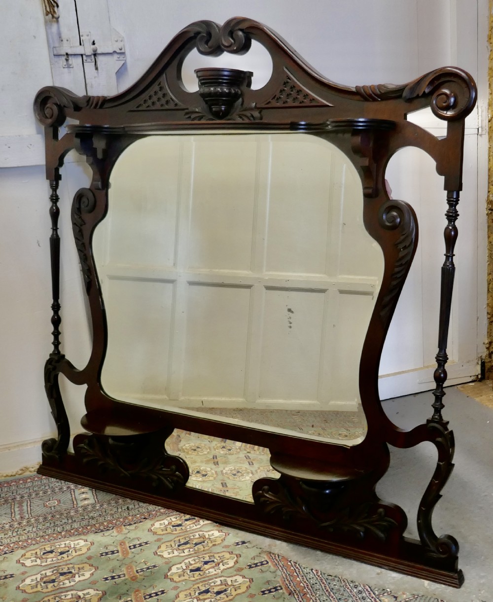 A large carved mahogany overmantel mirror in the Chinese Chippendale style, featuring pierced fretwork, turned side supports, side display shelves, and a shaped glass plate. View III