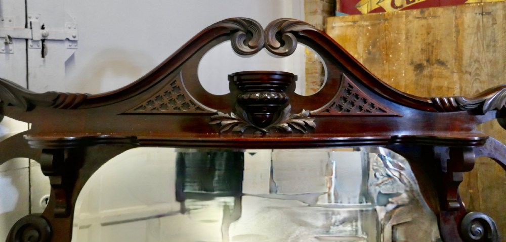A large carved mahogany overmantel mirror in the Chinese Chippendale style, featuring pierced fretwork, turned side supports, side display shelves, and a shaped glass plate. View IV