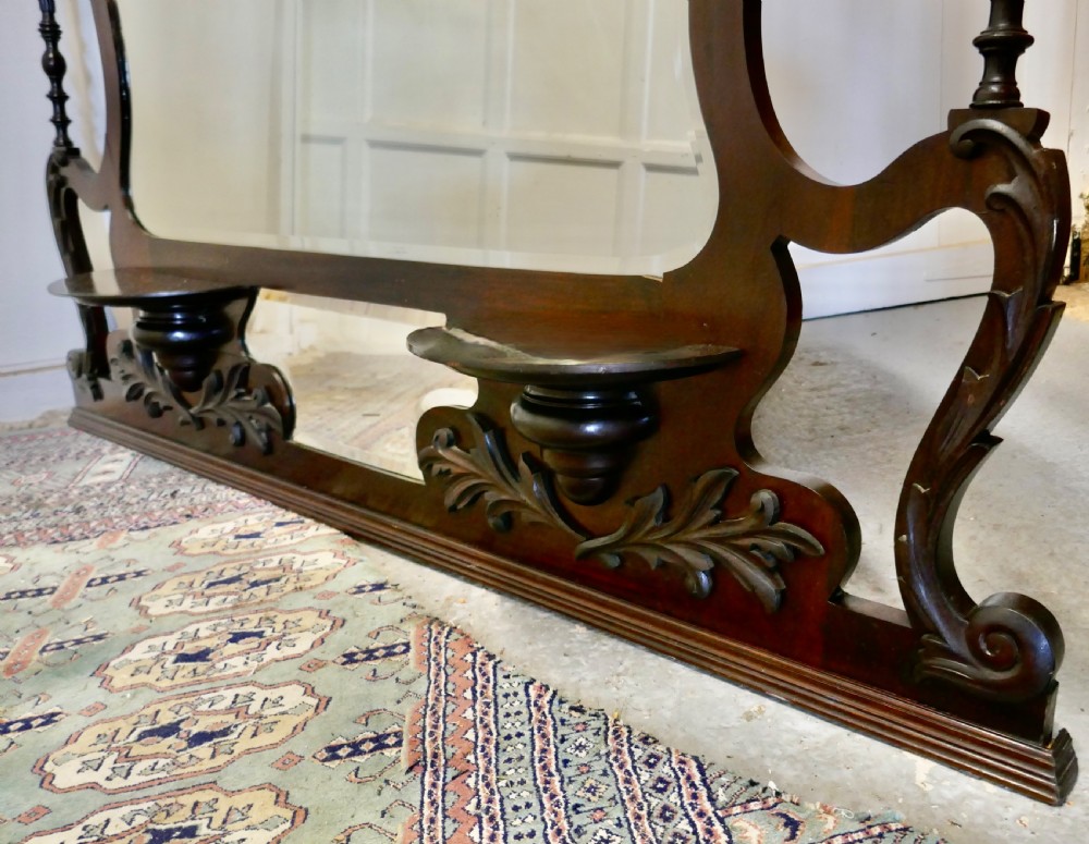 A large carved mahogany overmantel mirror in the Chinese Chippendale style, featuring pierced fretwork, turned side supports, side display shelves, and a shaped glass plate. View VI