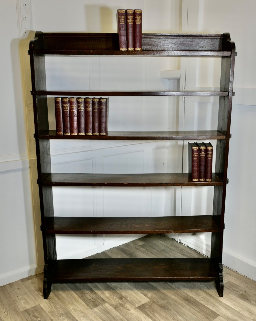 A tall open-front Arts and Crafts dark oak bookcase with six horizontal shelves and shaped side gallery rails. View II
