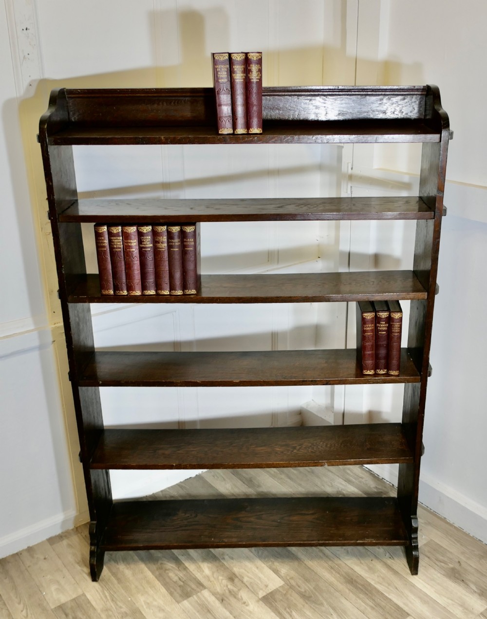 A tall open-front Arts and Crafts dark oak bookcase with six horizontal shelves and shaped side gallery rails. View III