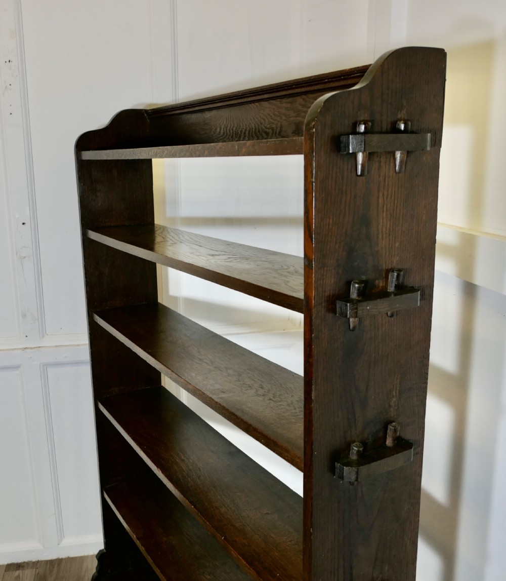 A tall open-front Arts and Crafts dark oak bookcase with six horizontal shelves and shaped side gallery rails. View VI