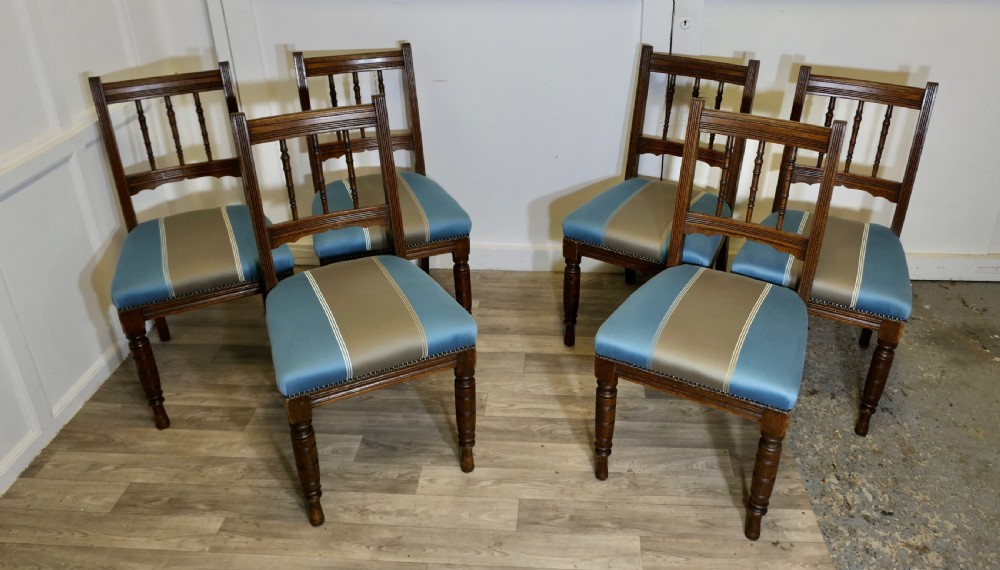 A set of six Edwardian oak dining chairs featuring turned front legs, vertical back spindles, and blue and grey striped satin seats with stud detail. View II
