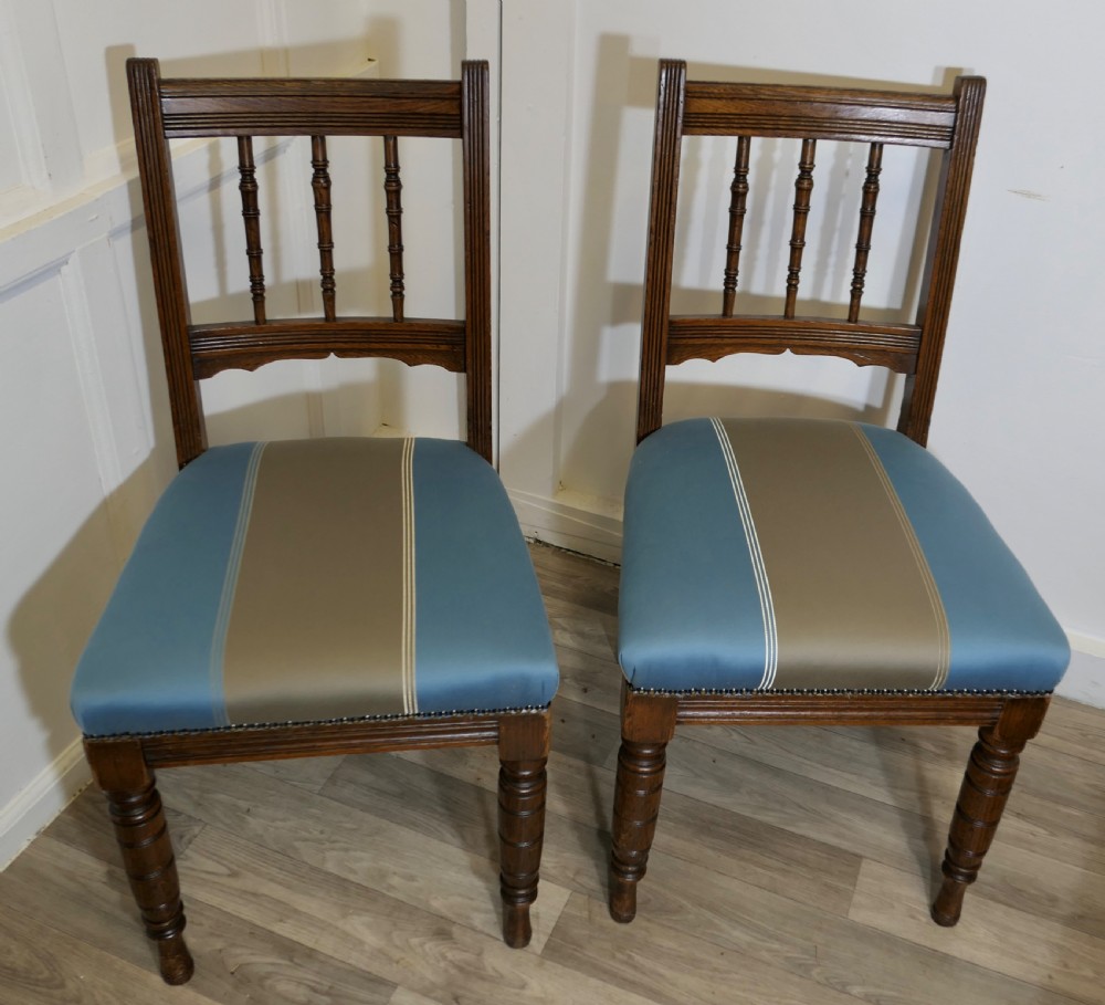 A set of six Edwardian oak dining chairs featuring turned front legs, vertical back spindles, and blue and grey striped satin seats with stud detail. View VI