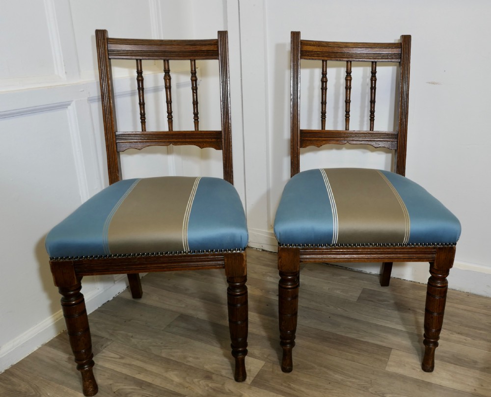A set of six Edwardian oak dining chairs featuring turned front legs, vertical back spindles, and blue and grey striped satin seats with stud detail. View VII