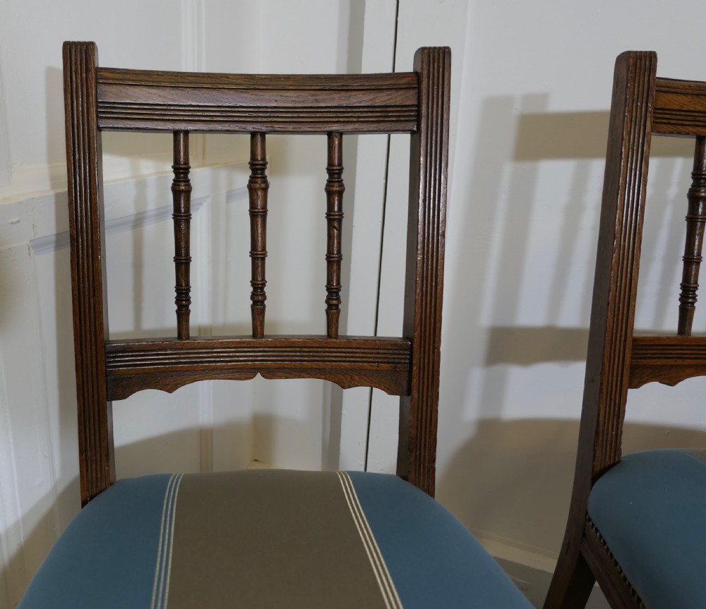 A set of six Edwardian oak dining chairs featuring turned front legs, vertical back spindles, and blue and grey striped satin seats with stud detail. View VIII
