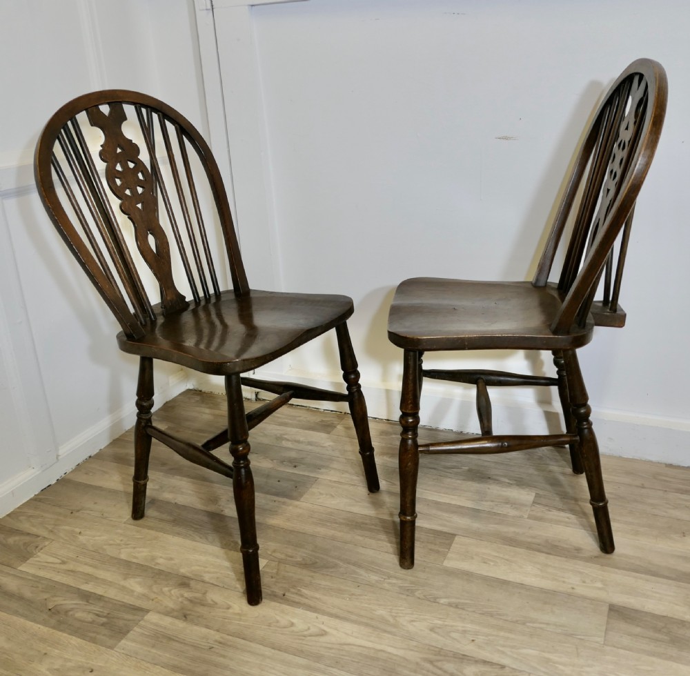 A pair of dark brown Victorian beech and elm chairs featuring wheelback pierced splats, turned legs, and contoured wooden seats. View IV