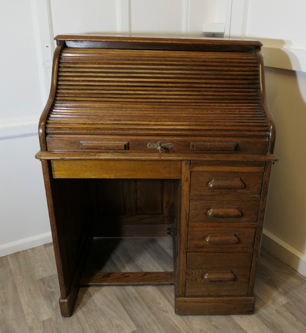 An Art Deco oak roll top desk featuring a flexible tambour shutter, fitted internal cubbies, and a single pedestal with four stacked drawers. View III