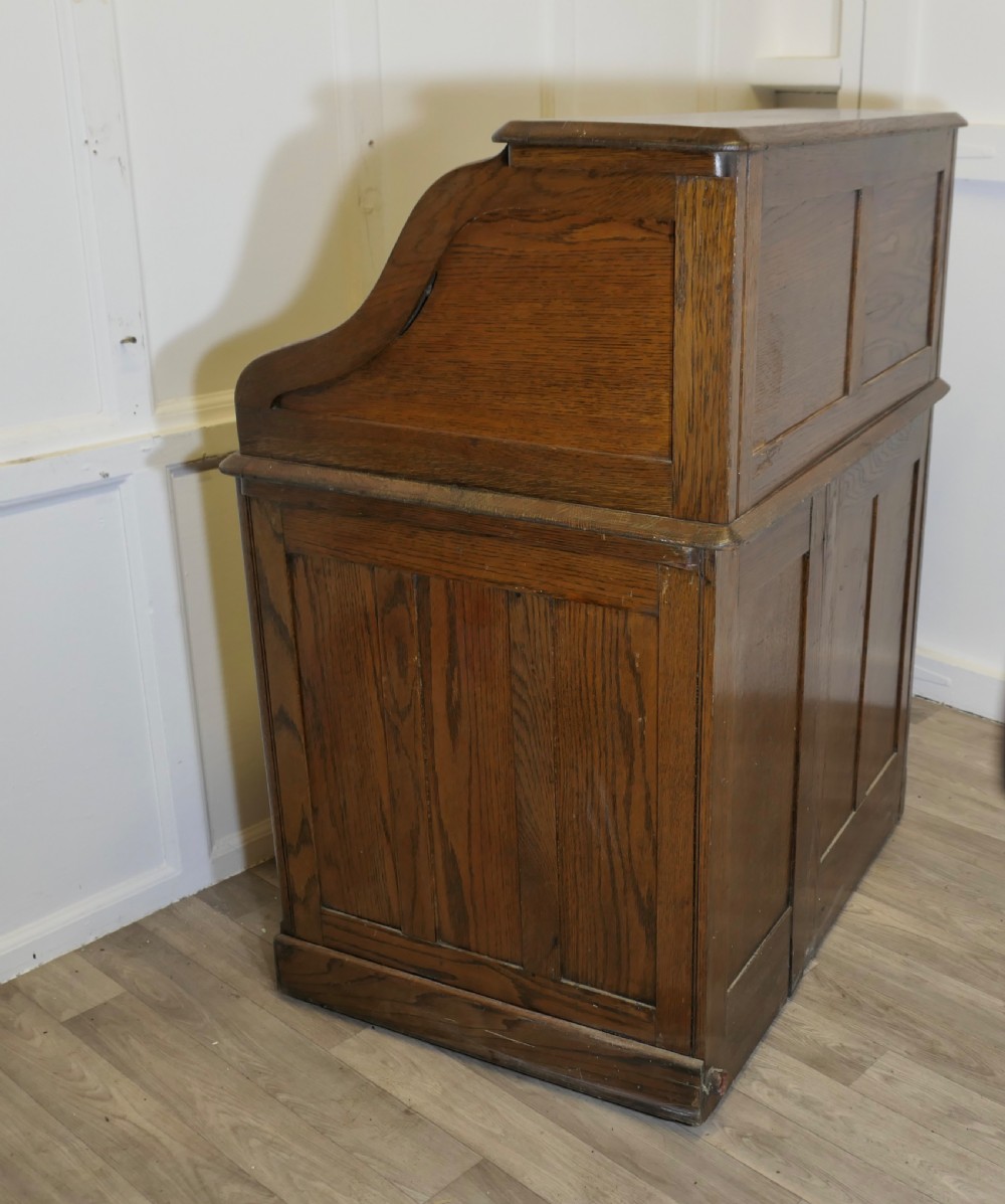 An Art Deco oak roll top desk featuring a flexible tambour shutter, fitted internal cubbies, and a single pedestal with four stacked drawers. View IX