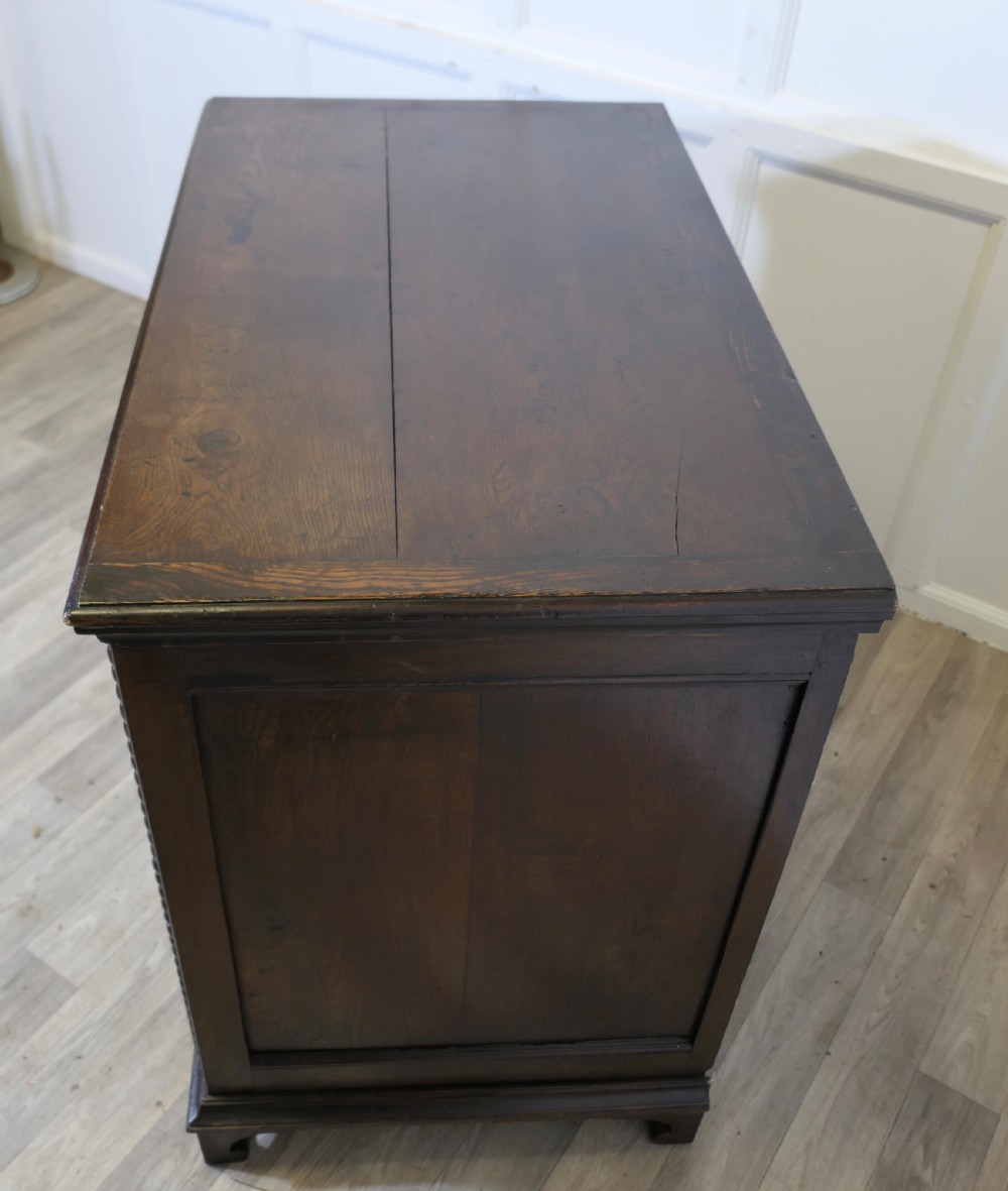 A dark oak chest of drawers featuring geometric moulded drawer fronts, vertical beaded moulding, and brass tear-drop handles. View III