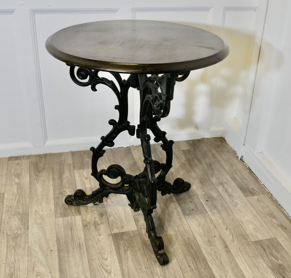 A Victorian occasional table with a dark polished circular wooden top mounted on an ornate black cast iron tripod scrollwork base. View III