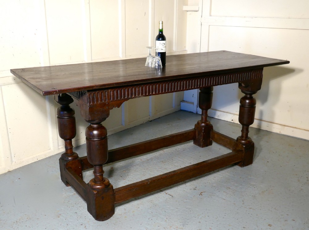 A 19th-century dark oak refectory table featuring turned legs, a carved fluted apron, and a low box stretcher. View XI