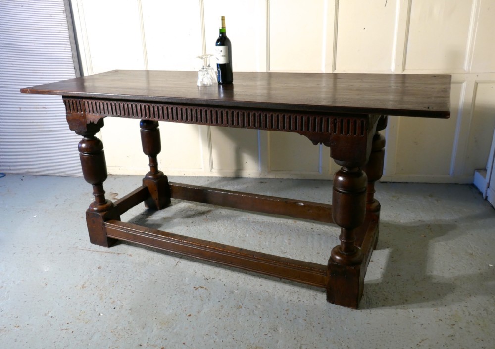A 19th-century dark oak refectory table featuring turned legs, a carved fluted apron, and a low box stretcher. View XIV