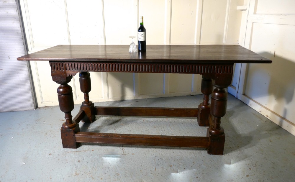 A 19th-century dark oak refectory table featuring turned legs, a carved fluted apron, and a low box stretcher. View XV