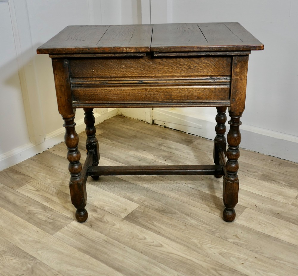 A dark oak joint stool featuring a rectangular plank top, a moulded frieze, turned legs, and a low perimeter stretcher base.